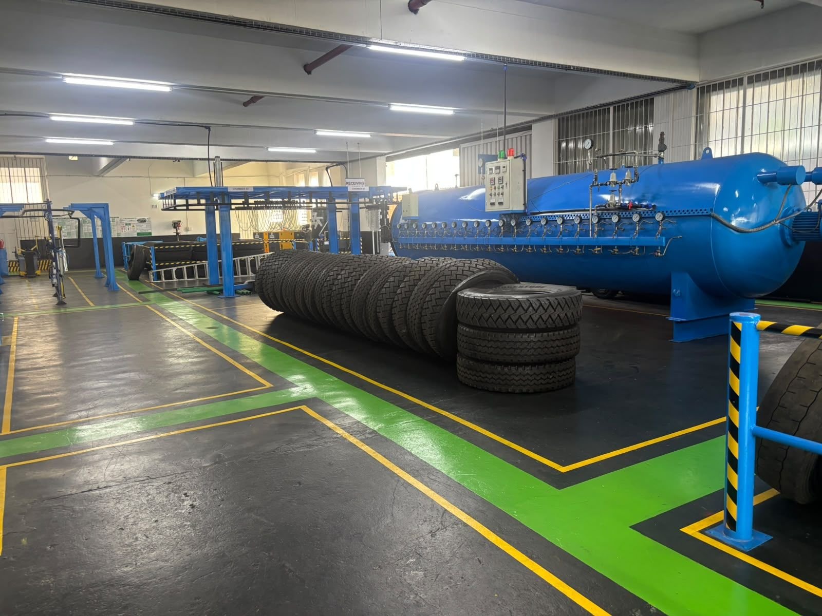 Blue curing chamber with retreaded truck tyres lined up beside it